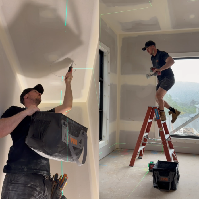 Two men working on a ceiling in a room with drywall and tools.