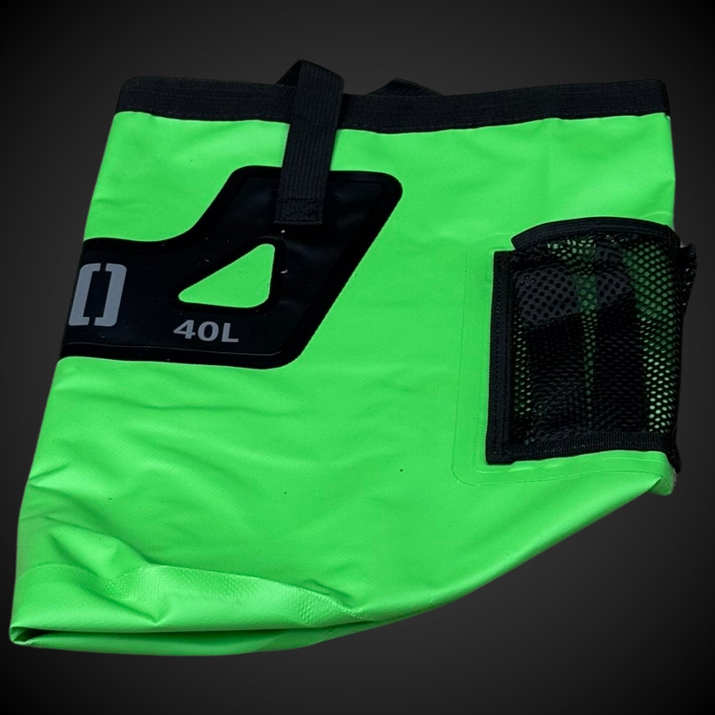 Green bag with black straps and mesh pocket on a dark background