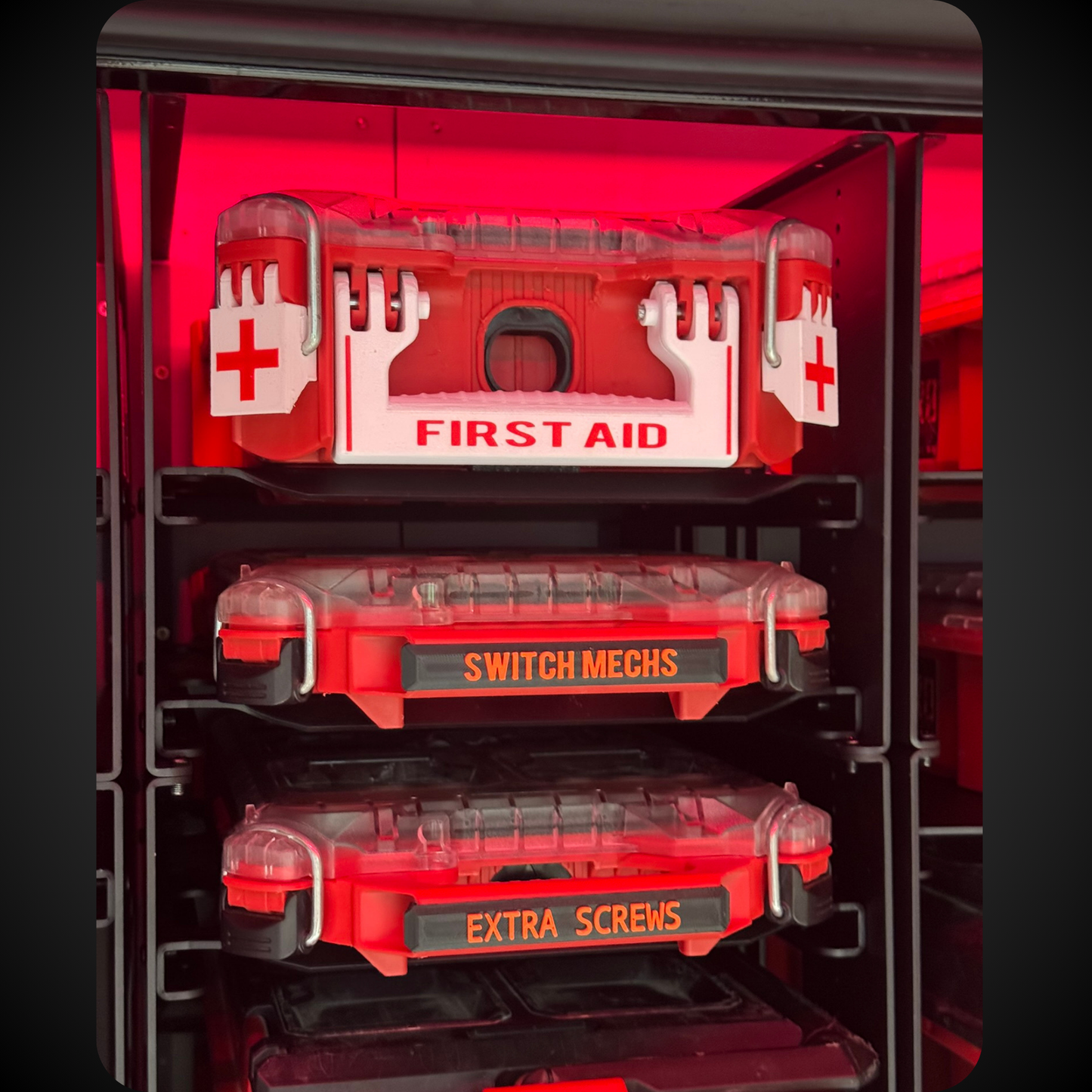 Red tool organizer with compartments labeled 'First Aid', 'Switch Mechs', and 'Extra Screws' on a black background.