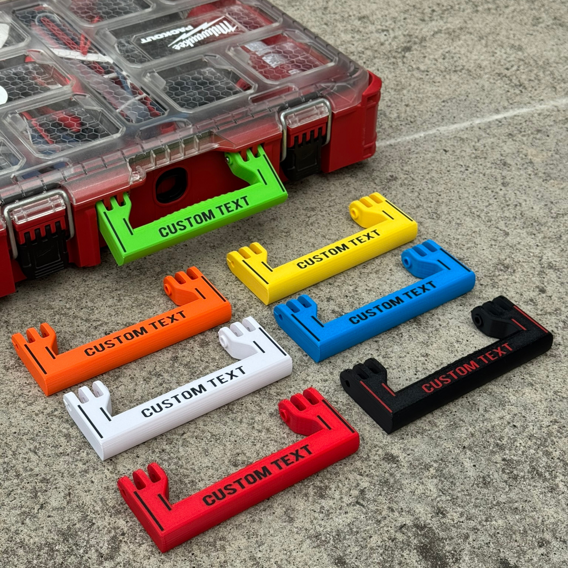 Custom handles for Milwaukee Standard Packout boxes, displayed in multiple colors including red, black, orange, white, blue, and green, with 'CUSTOM TEXT' printed on each Handle - Standard Full Width.