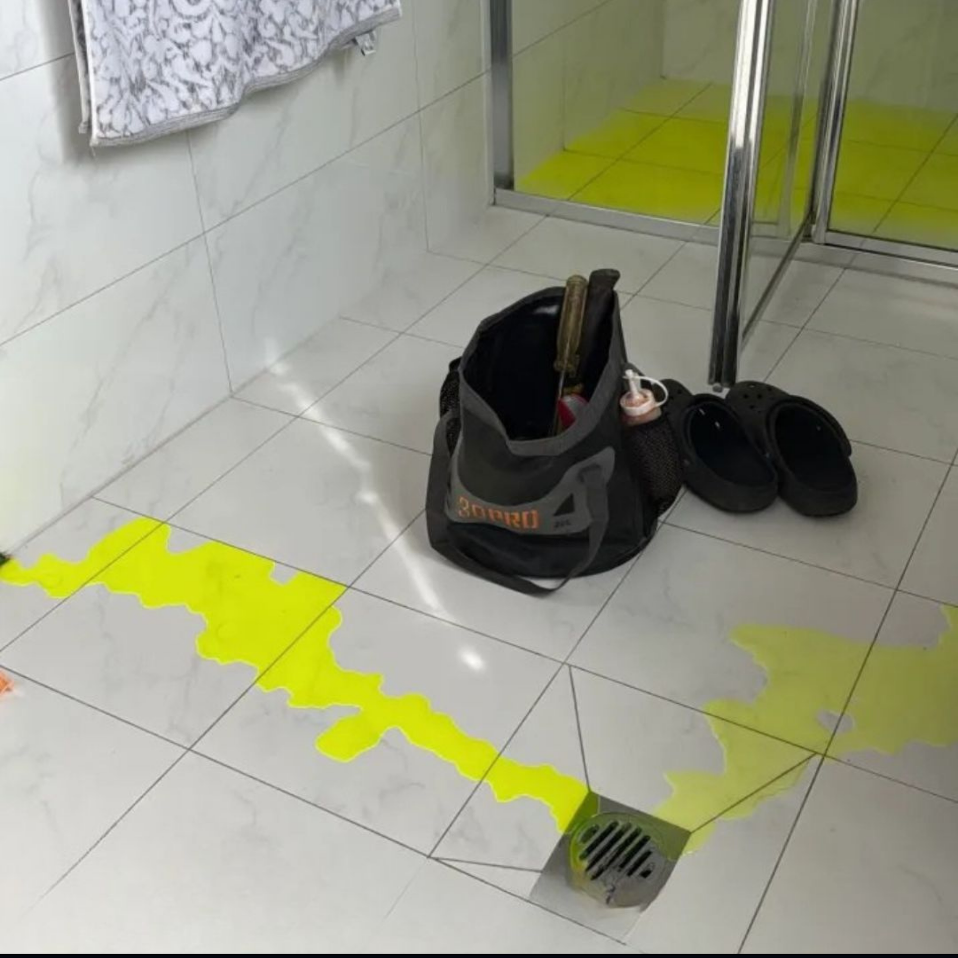 Folding buckets with tools on a tiled floor next to a shower area