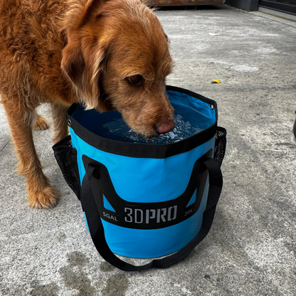 Dog drinking from a blue 3DPRO water bag on a concrete surface