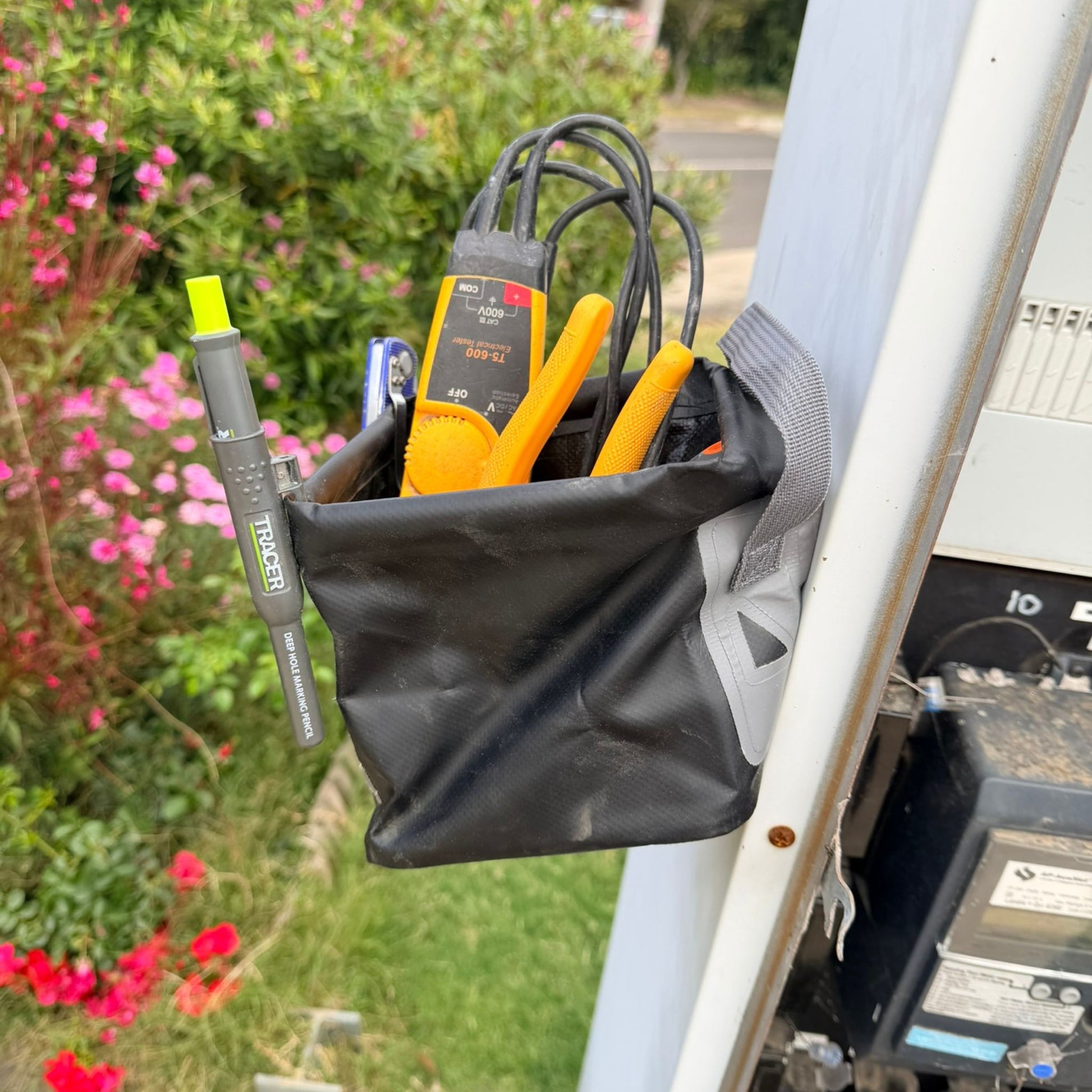Black 3L Pro Magnetic Folding Bucket with electrical testing equipment attached to a vehicle, with flowers and greenery in the background.