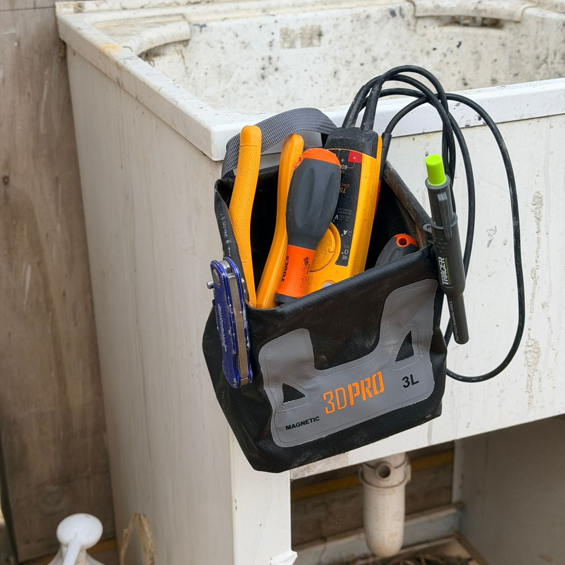 3L Pro Magnetic Folding Bucket On Site with tools hanging on a wall-mounted cabinet in a construction setting