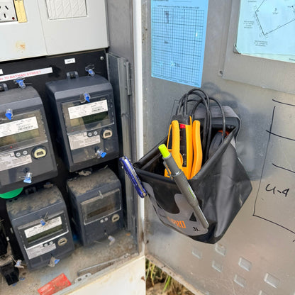 Electrical panel with meters and a 3L Pro Magnetic Folding Bucket On Site containing tools and a pen.