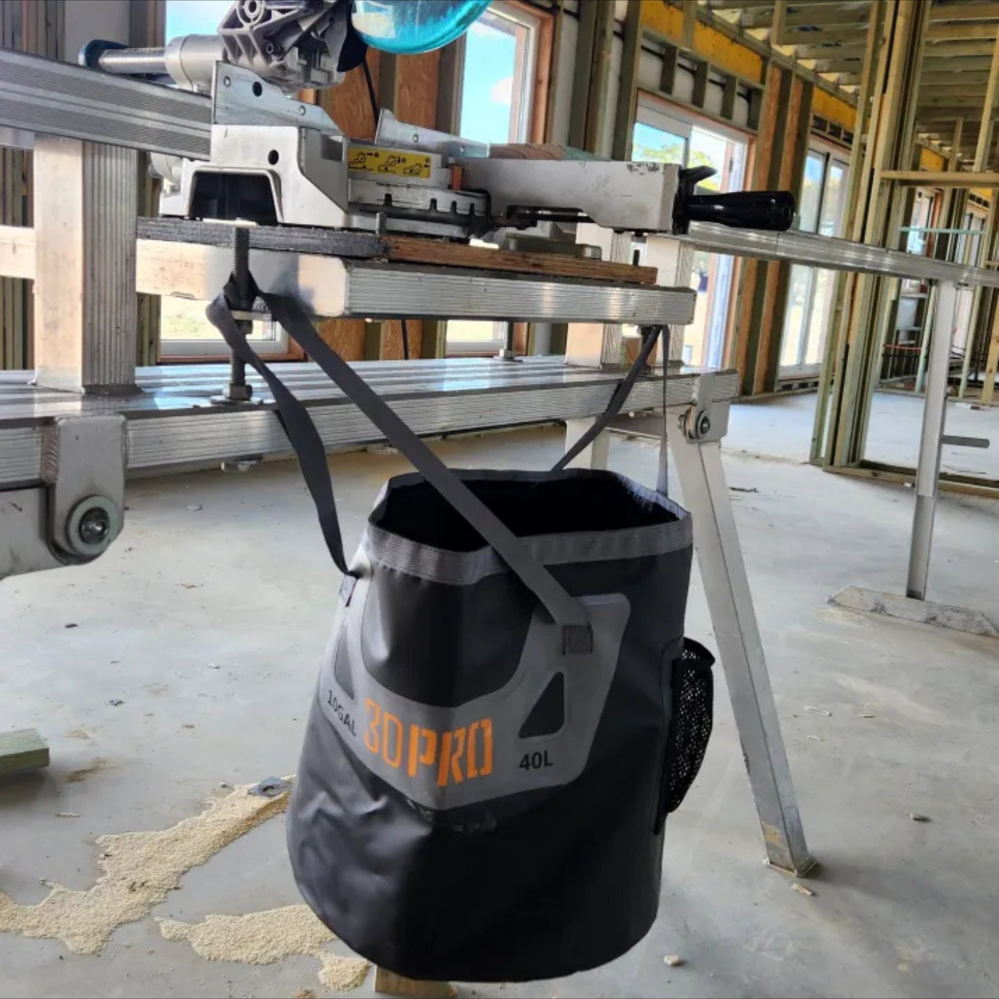 Black and gray bucket labeled '3DPro' on a construction site with a metal table in the background.
