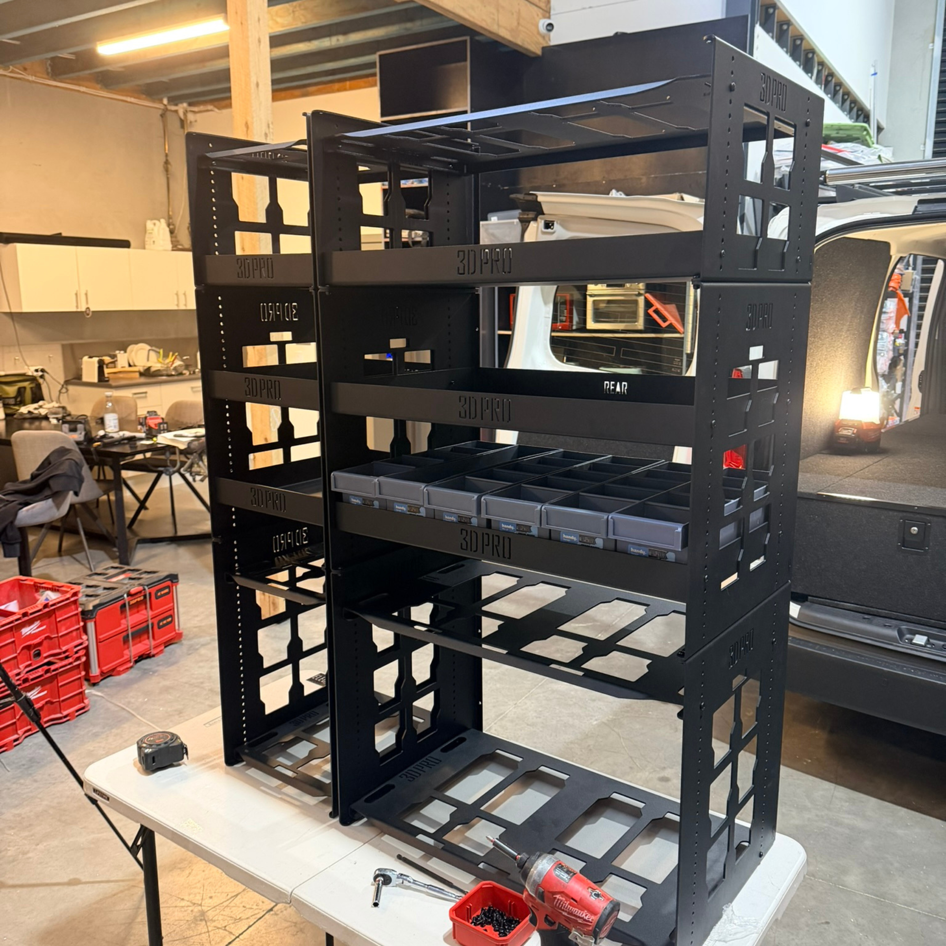 Black metal storage rack with shelves in a workshop setting