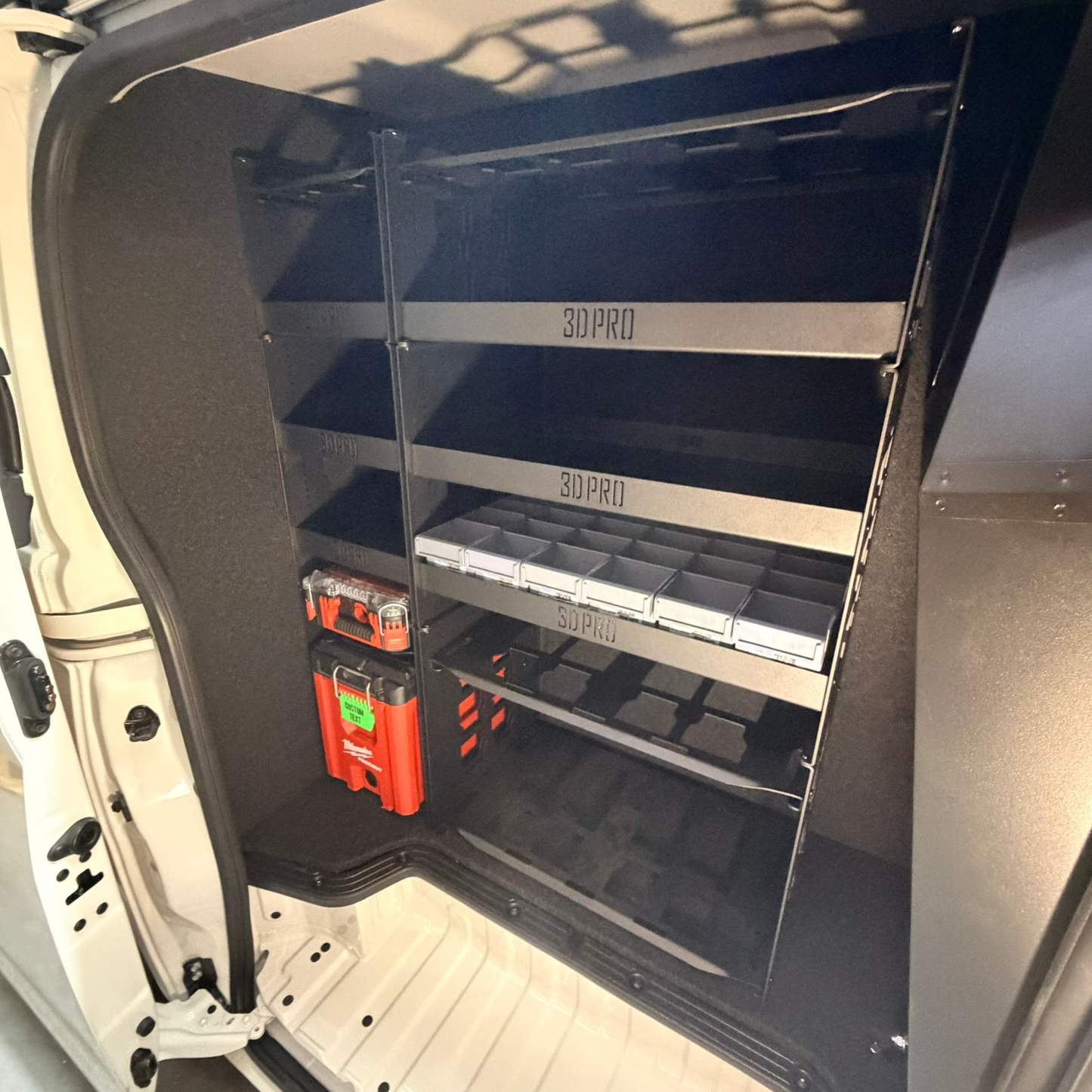 Shelving system inside a vehicle with tools and equipment on shelves.