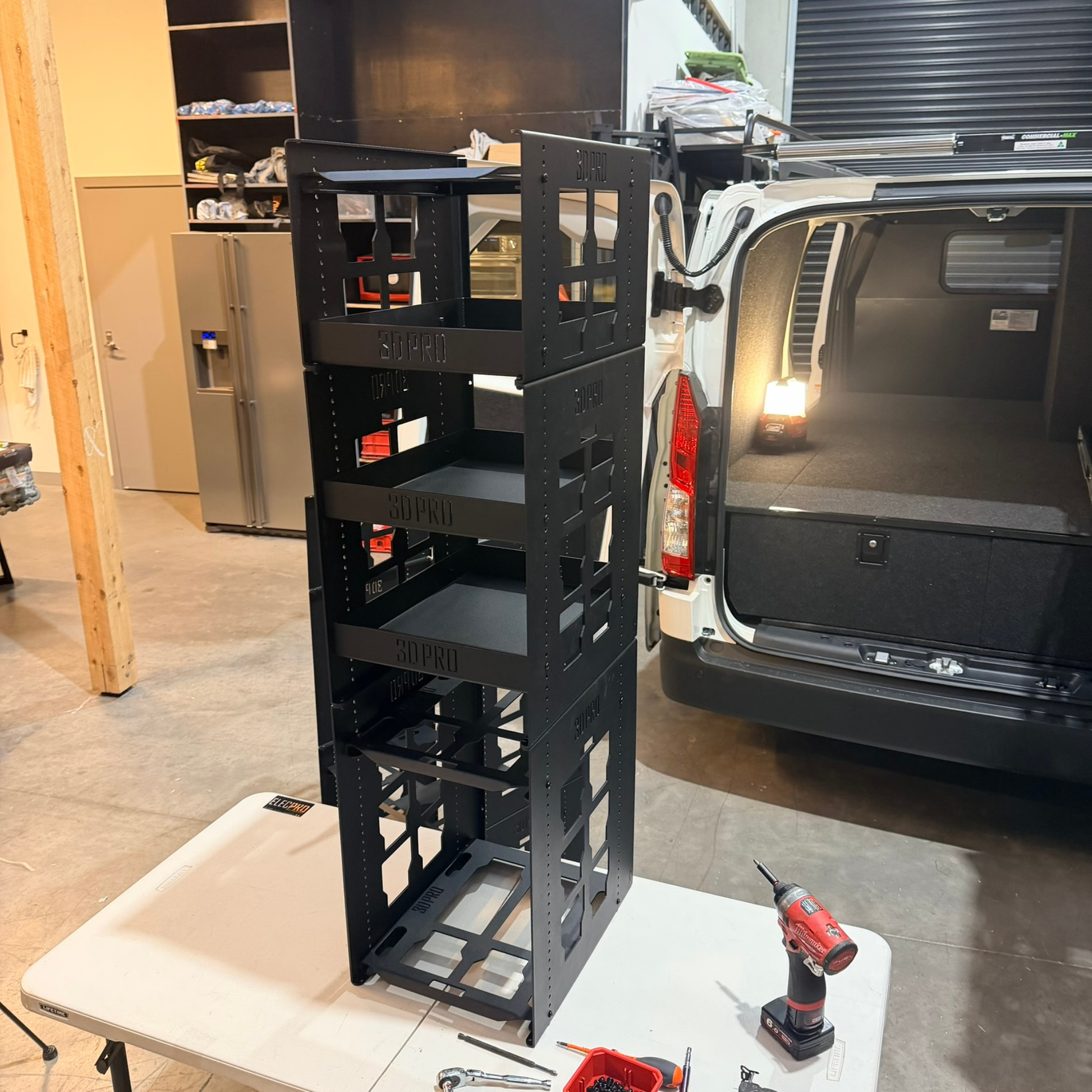 Black metal shelf with tools on a white table in a garage setting