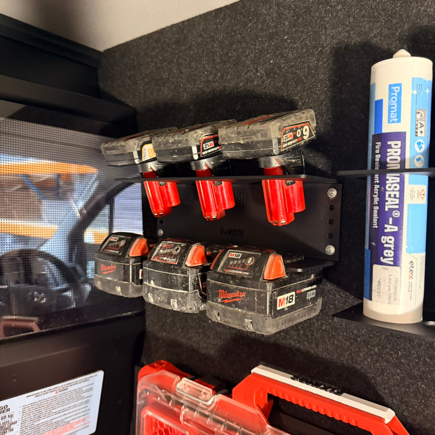 Set of Milwaukee tool batteries on a shelf with a can of spray paint in the background.