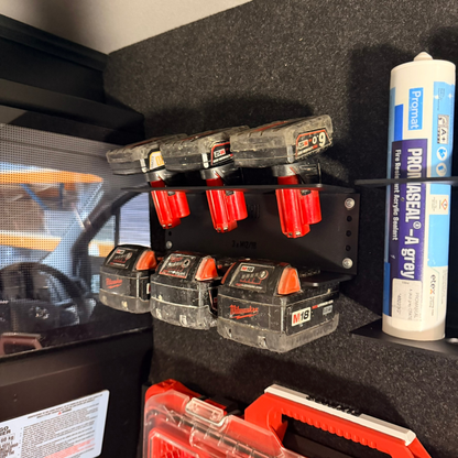 Set of Milwaukee tool batteries on a shelf with a can of spray paint in the background.