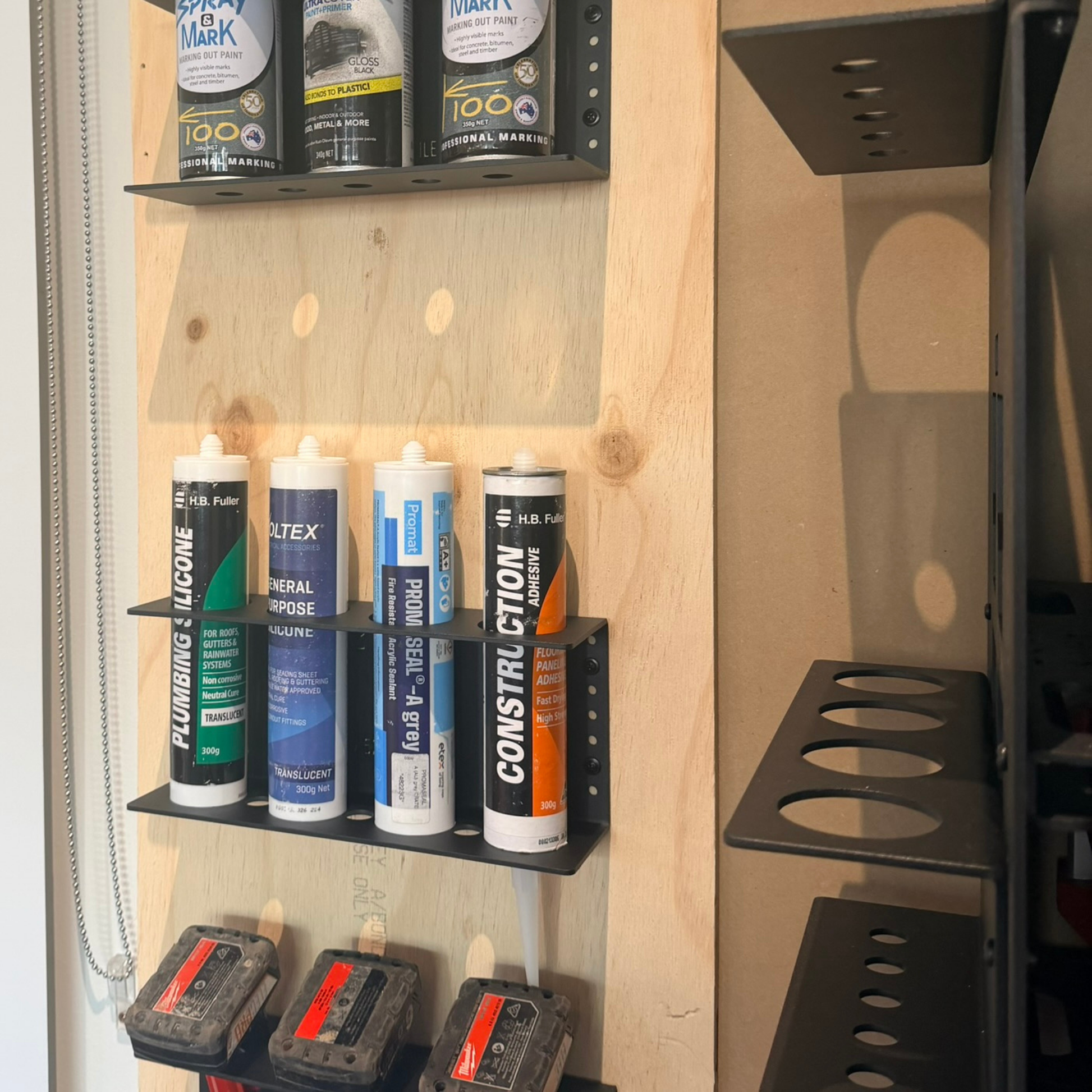 Shelves with various cans of paint and solvents on a wooden wall.