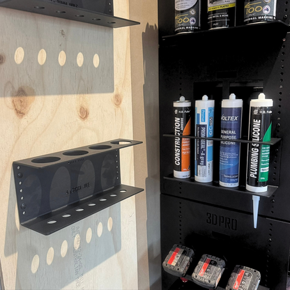 Quad Silicon Holder with various cans of spray paint and tools against a wooden wall.