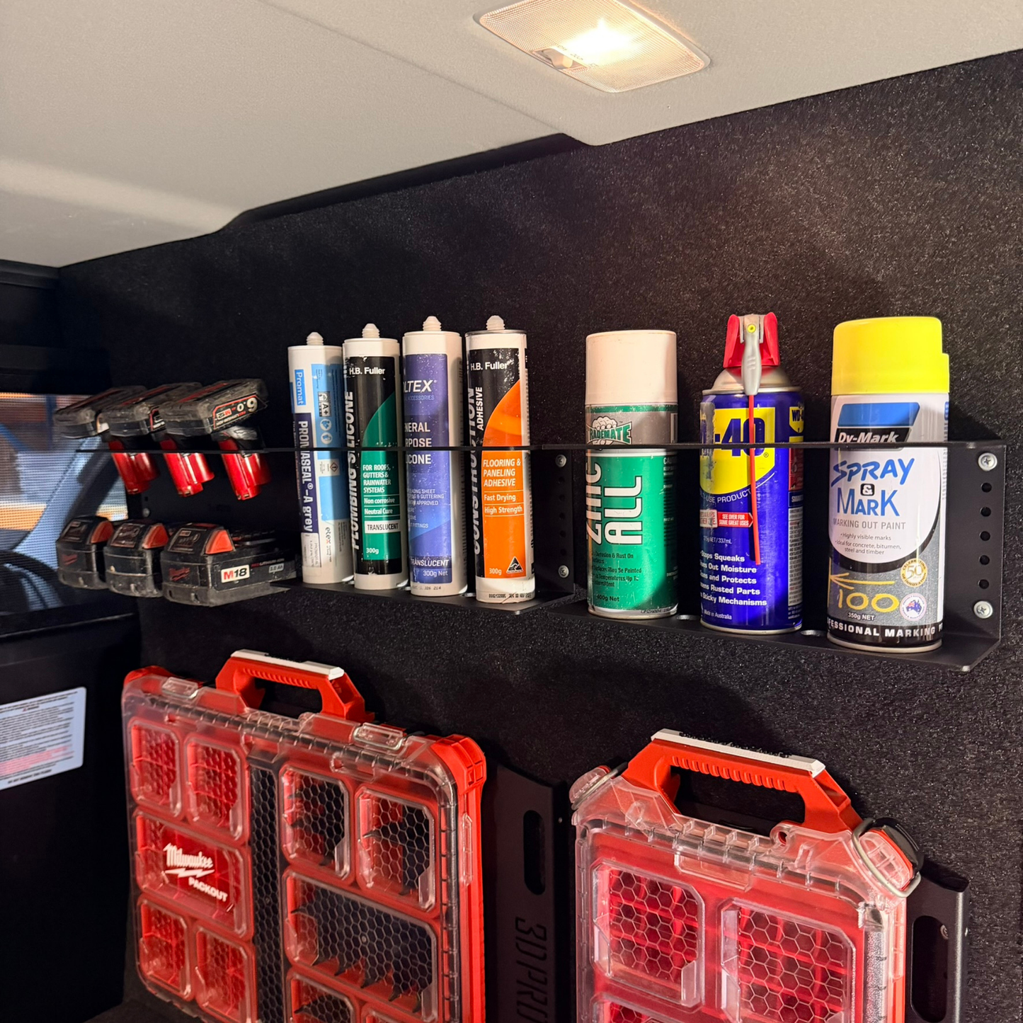 Collection of spray cans and toolboxes on a black shelf