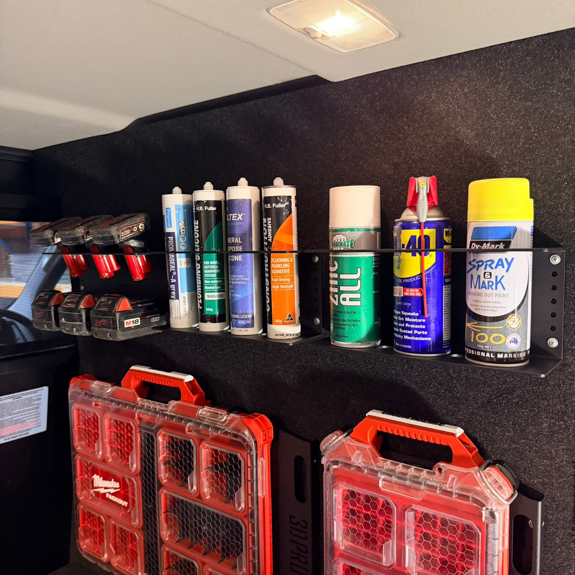 Collection of spray cans and toolboxes on a black shelf